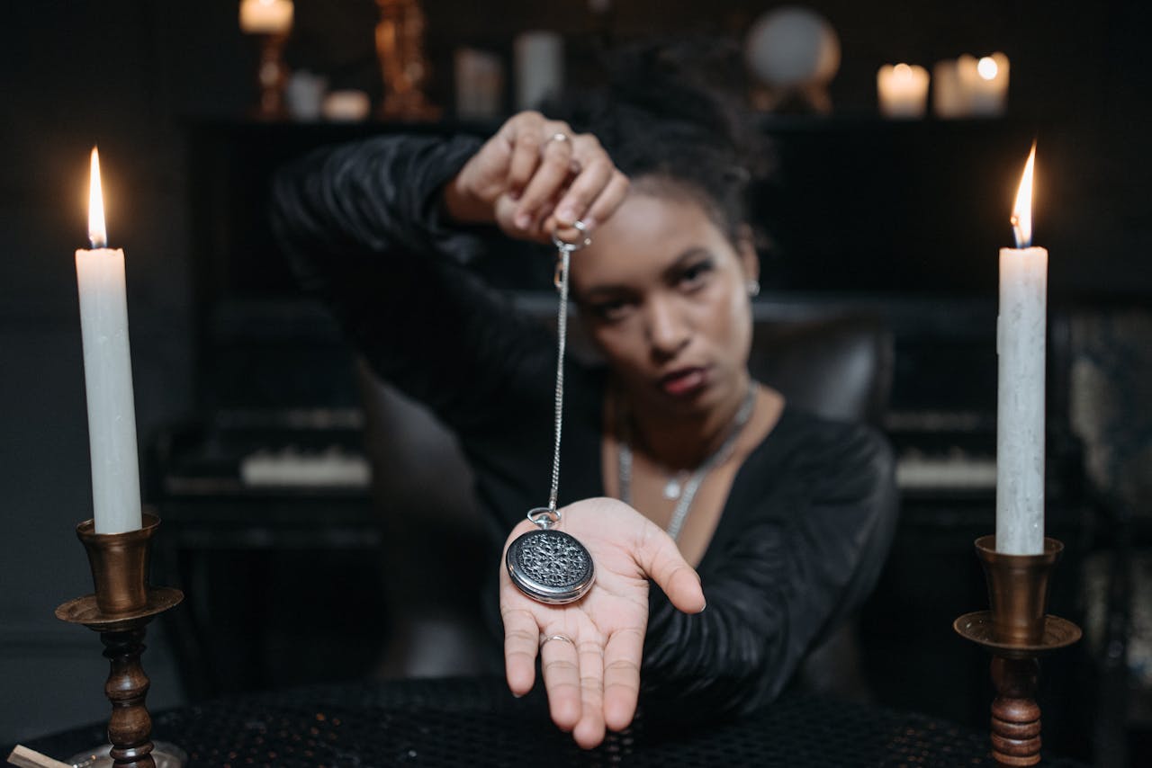 A woman holding a pendant during a mystical seance with candlelight.